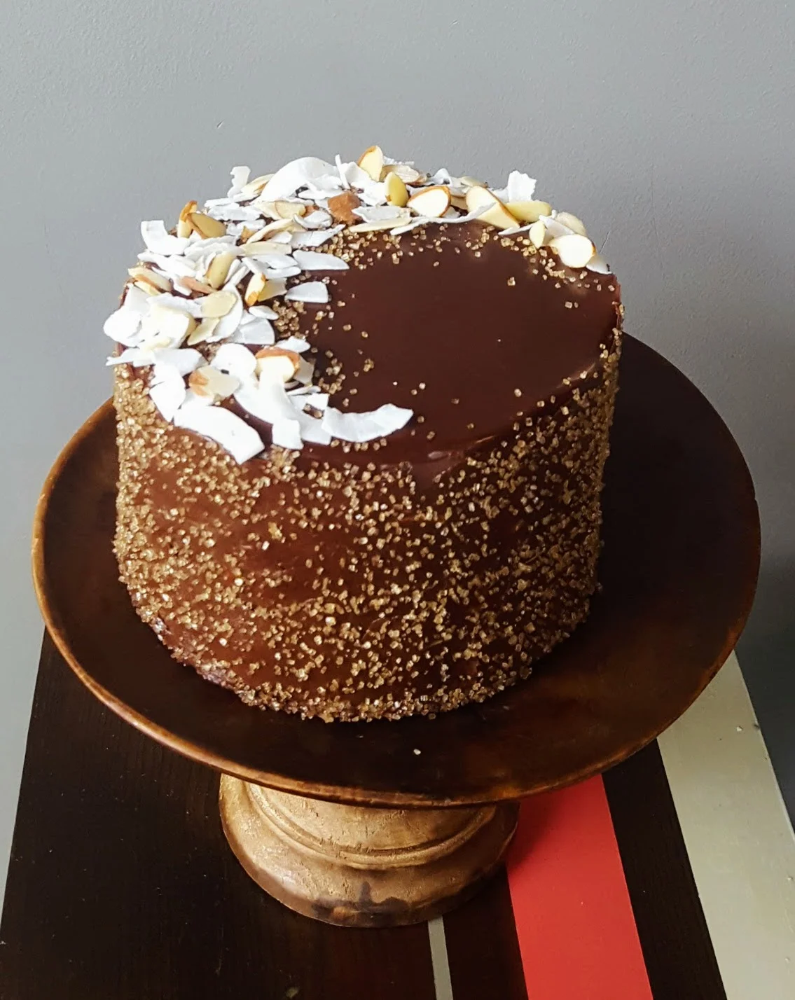 Round layered cake with glossy chocolate glaze and gold sanding sugar