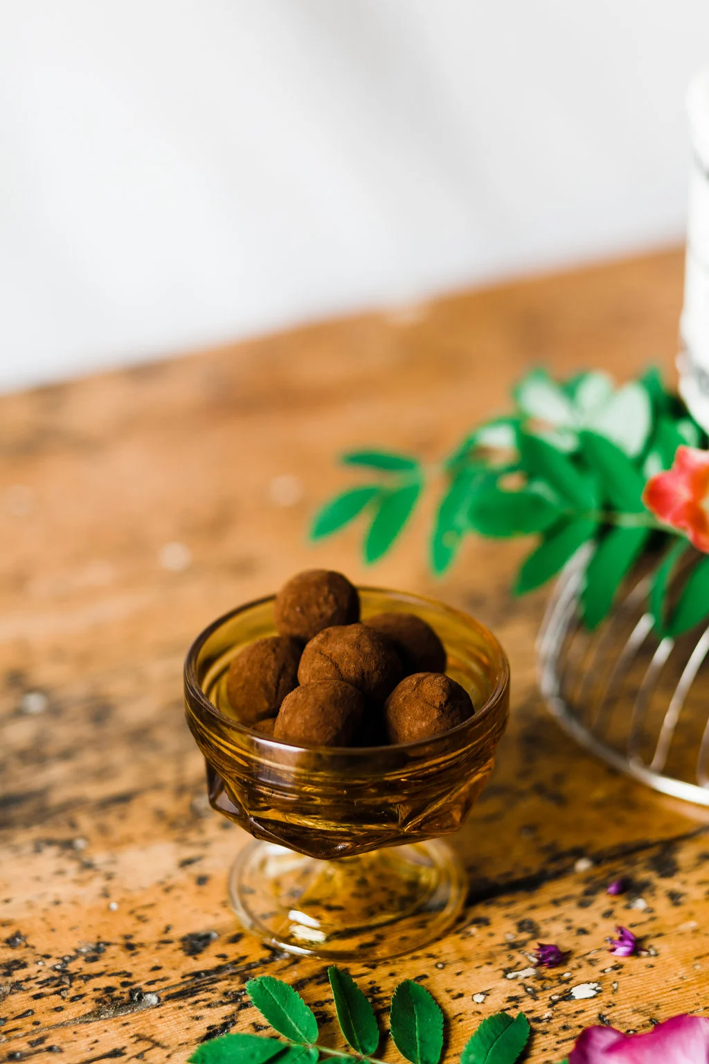 Small glass dish of chocolate truffles dusted with cocoa on a wooden surface