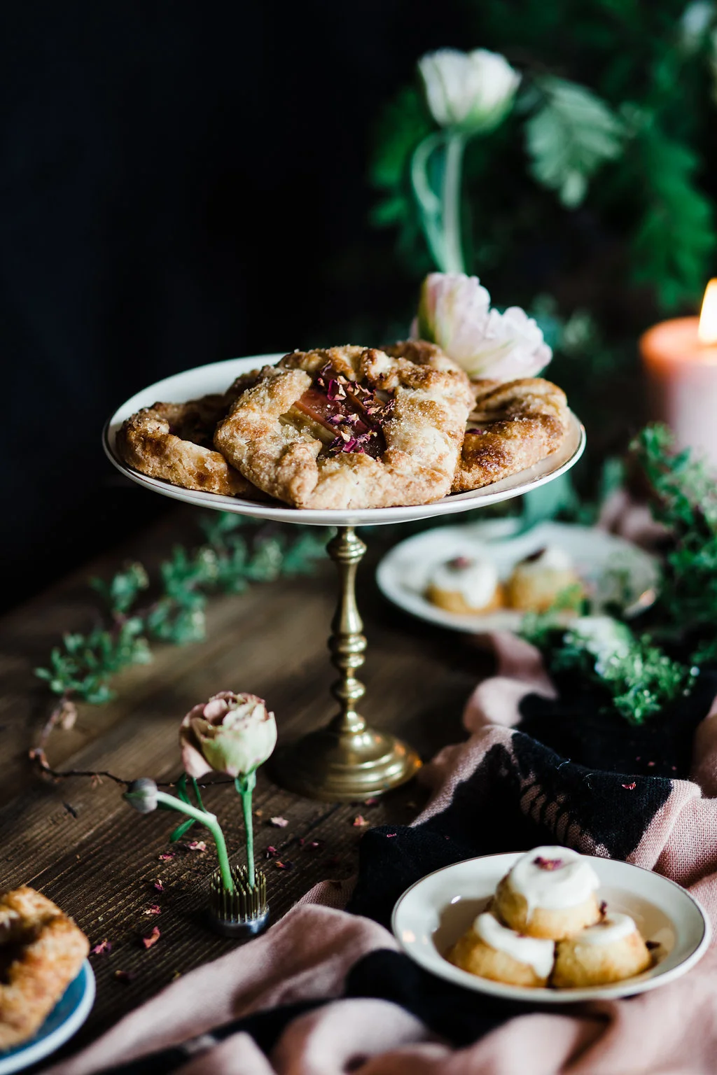 Golden fruit-filled pastries on a pedestal plate in a moody dark setting